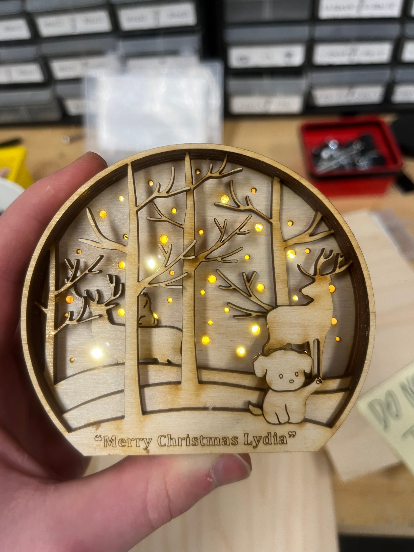 Laser-cut layered wooden light-up ornament of a winter forest, engraved 'Merry Christmas Lydia'